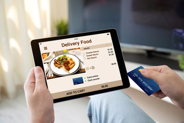 male hands holding bank card tablet with app delivery food