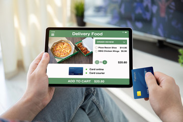 male hands holding bank card tablet with app delivery food