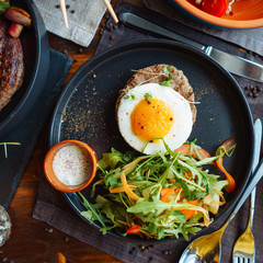 Beefsteak with egg and salad from greens and vegetables