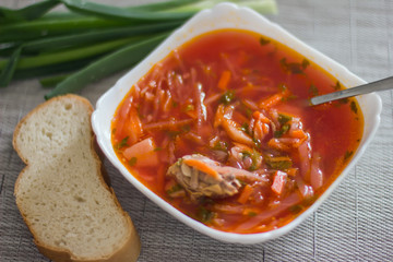 Ukrainian beetroot soup - borscht in a white bowl on the kitchen table. Delicious beet soup. Fresh borsch on the table surrounded by products