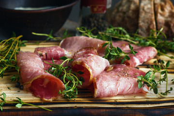 delicious pork bacon sliced ​​into strips on a wooden background with spices and fresh thyme. A serving of low-fat succulent farm meat pork. Food Photography