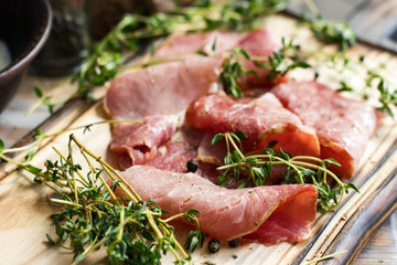 Delicious flavorful ham sliced ​​into strips on a wooden background with spices and fresh thyme. A serving of low-fat succulent farm meat pork. meat product. Food Photography