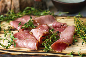 Delicious flavorful ham sliced ​​into strips on a wooden background with spices and fresh thyme. A serving of low-fat succulent farm meat pork. meat product. Food Photography