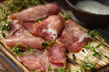 delicious pork bacon sliced ​​into strips on a wooden background with spices and fresh thyme. A serving of low-fat succulent farm meat pork. Food Photography