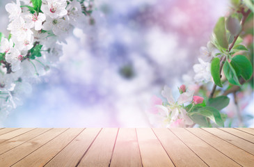 Empty wooden table, natural delicate flowers in the background, sun rays. Light delicate floral background pattern