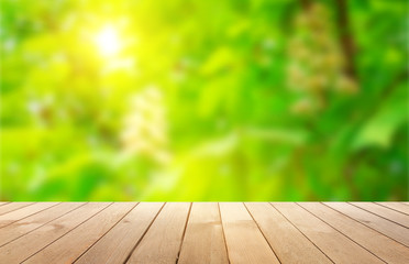 Empty wooden table, natural blurred greens on the background, the sun's rays