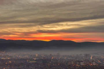 Naklejka premium Stunning, soft view of burning sunset sky above scenic cityscape covered by haze and mist