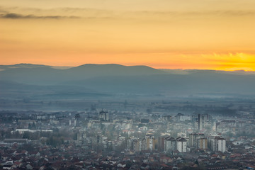 Amazing sunset sky over Pirot cityscape and misty horizon mountains