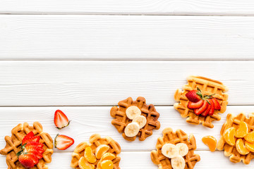 Fototapeta na wymiar Breakfast with Belgian waffles with strawberry, tangerine and banana topings on white wooden background top view mockup