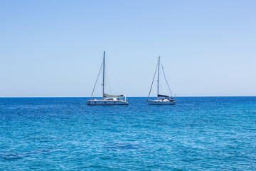 Fototapeta premium yachts on calm vivid blue water surface of Mediterranean sea near south Greece coast, cruise and summer rest picture in clear weather time, copy space 