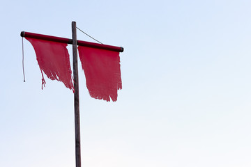 medieval vertical red flag with flagpole. red flag on a flagpole against a blue sky. Peace. After the battle. The end of the debate.