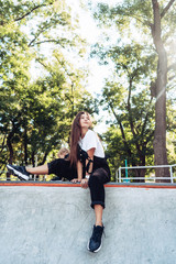 Beautiful young hipster girl sitting on the edge of a ramp