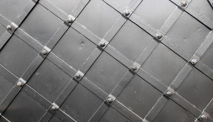Antique metal black abstract background of diagonal stripes and screws at intersections.