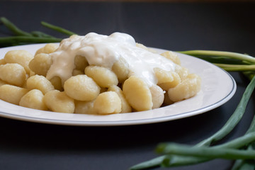 Dish of Italian gnocchi decorated with green onion feathers. Macro side view