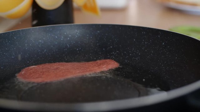 A panning shot from left to right of a ration of Quorn veggie & vegan bacon being put into a hot frying pan full of sizzling oil, a great breakfast supplement for national vegetarian week.
