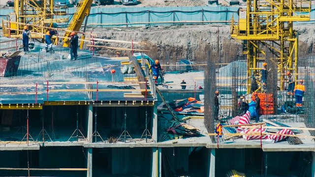 Time lapse builders and cranes working on the construction site close up, zoom out
