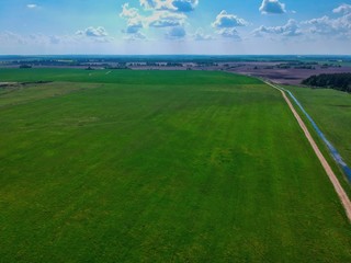aerial view of a field with blue sky and clouds in Minsk Region of Belarus