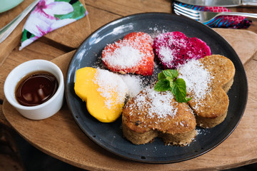 Oatmeal Pancakes and tropical fruits in the form of a heart with mint and honey on wooden table. Valentine's Day. Healthy food concept
