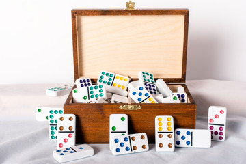 wood box full of jumbo white dominoes with colored dots on white background