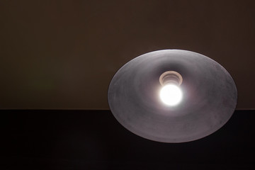 Lamp turned on under a metal ceiling on a dark background of the ceiling
