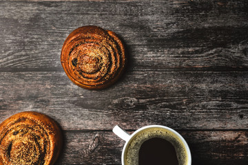 Perfect breakfast of homemade cinnamon buns and coffee on wooden table. Rustic style. Top view.