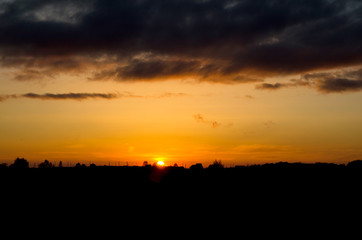 Beautiful sunset under the forest and dark clouds