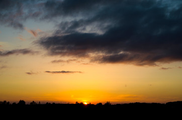Fototapeta premium Beautiful sunset under the forest and dark clouds