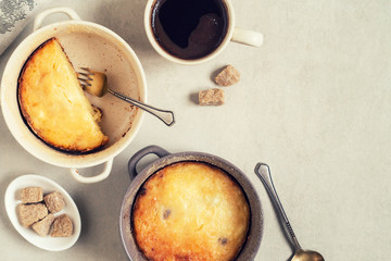 Two pans with cottage cheese casserole and cup of coffee on gray table