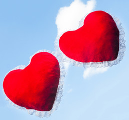 Fototapeta premium Two red heart shaped cushions against the sky
