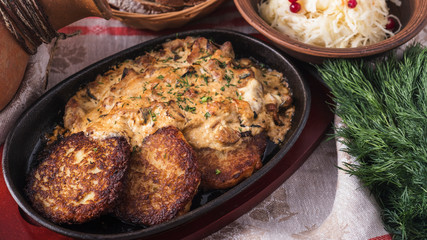 Potato pancakes with  sour cream sauce and mushrooms on a frying pan.  National food