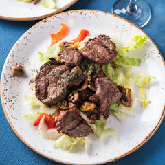Meat salad with fresh vegetables on a plate. Top view. Closeup