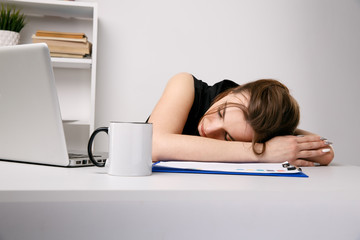 Obraz premium Exhausted woman sleeping at her office desk near the computer