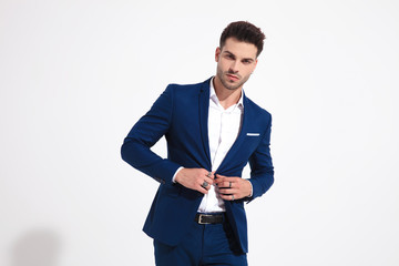 Elegant man looking to the camera and adjusting his jacket