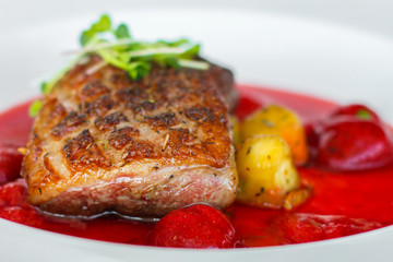fried duck breast with berry sauce and vegetables (main dish). food background. top