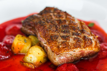 fried duck breast with berry sauce and vegetables (main dish). food background. top