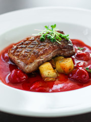 fried duck breast with berry sauce and vegetables (main dish). food background. top