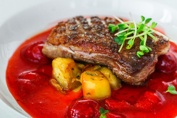 fried duck breast with berry sauce and vegetables (main dish). food background. top