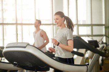 Young happy woman running on a treadmill. Young sportive woman training at modern gym. Always be in...
