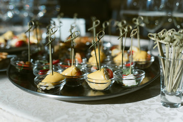 Fototapeta na wymiar Cocktail with champagne and small toasts on a skewer. Snacks from strawberry, cheese, olives