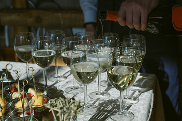 The waiter pours champagne in glasses at the celebration. Glasses of wine in the sun
