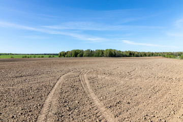 Traces of tractors on the plowed field in spring