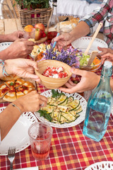 Obraz na płótnie Canvas Adult people enjoy food together. Hands take something on the table. Mix of vegetables, eggs and pizza. Family brunch