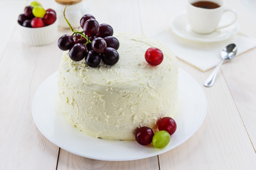 Homemade cake with cream cheese and fresh grapes on a white plate