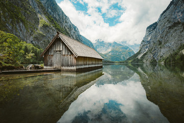 Fototapeta na wymiar Idyllic view of traditional old wooden boat house at scenic Lake Obersee on a beautiful sunny day with blue sky and clouds in summer, Nationalpark Berchtesgadener Land, Bavaria, Germany
