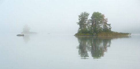 Small island on the lake in mist
