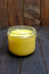 Ghee butter in a jar on wooden background, copy space