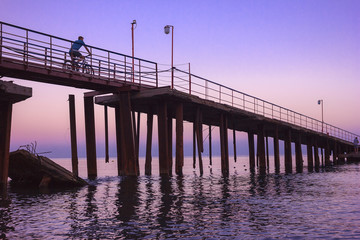 Obraz premium cyclist rides to the pier during sunset