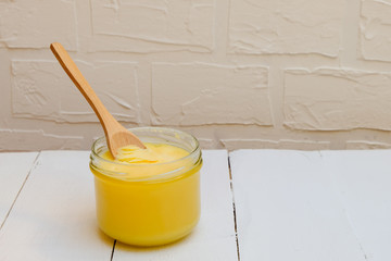 Ghee butter or clarified butter on a white background with wooden spoon, copy space