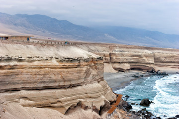 Fototapeta na wymiar Coastal cliffs La Portada near Antofagasta, northern Chile, on a hazy day of sand storm .