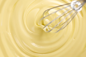 White chocolate. Melted liquid white chocolate mixing with a wisk. Closeup of molten liquid hot...